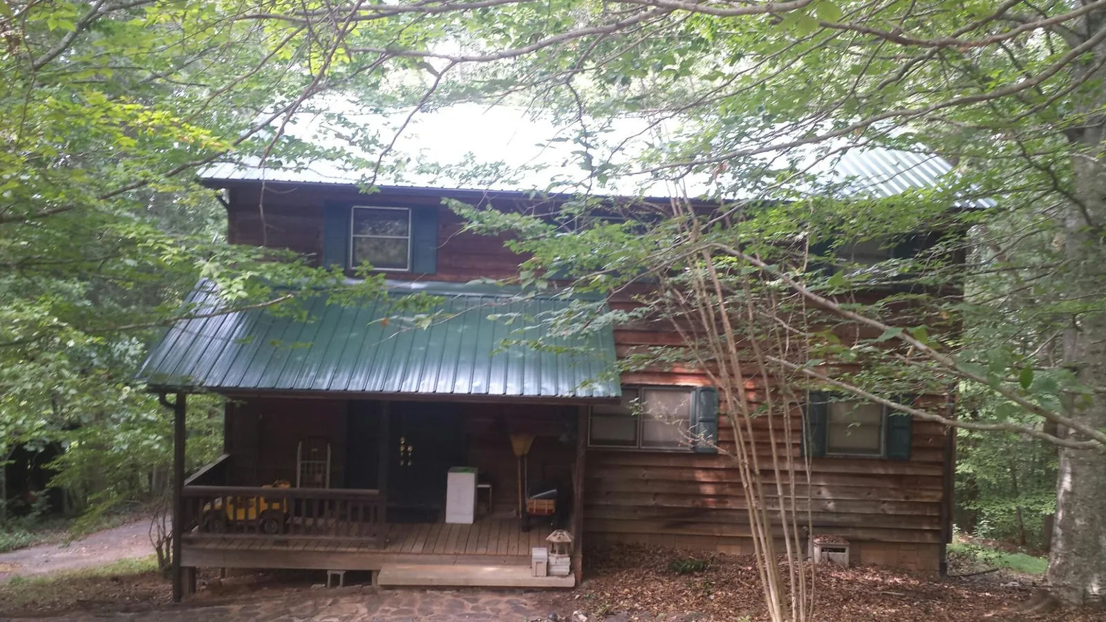 Green metal roof and covered porch on a log cabin in Sargeant