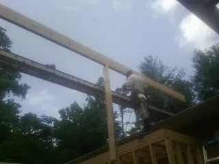 Carpenter setting a ridge beam over a new addition frame — Ice Dam Removal by Roofing Brothers in Sargeant