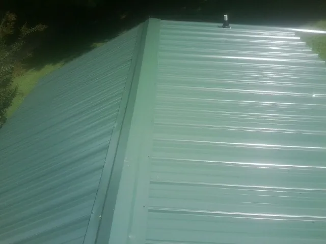New green metal panels meeting at the ridge of a roof — Flat Roof Repair work by our crew in Sargeant
