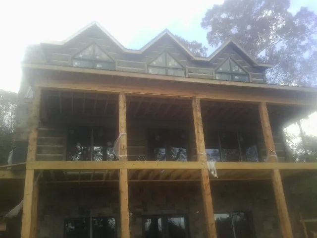 Dormers and porch framing on a large log home under construction — Roof Coating work by our crew in Sargeant