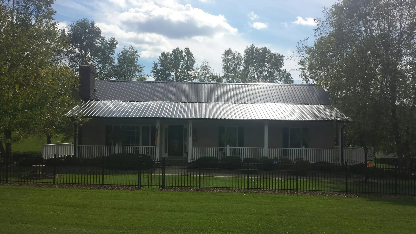 Gray metal roof on a brick ranch with a full width front porch — Gutter Guard Installation work by our crew in Sargeant