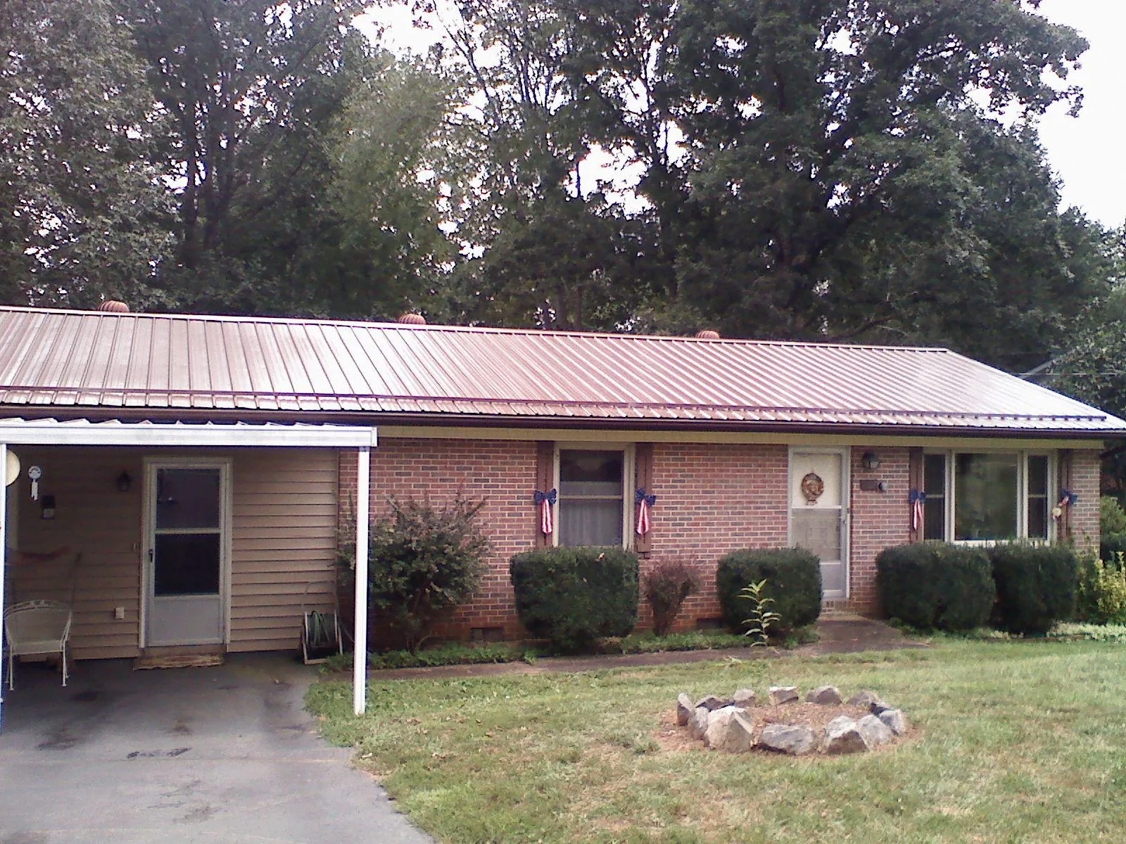 Bronze metal roof and carport on a brick ranch home — Roof Repair work by our crew in Sargeant